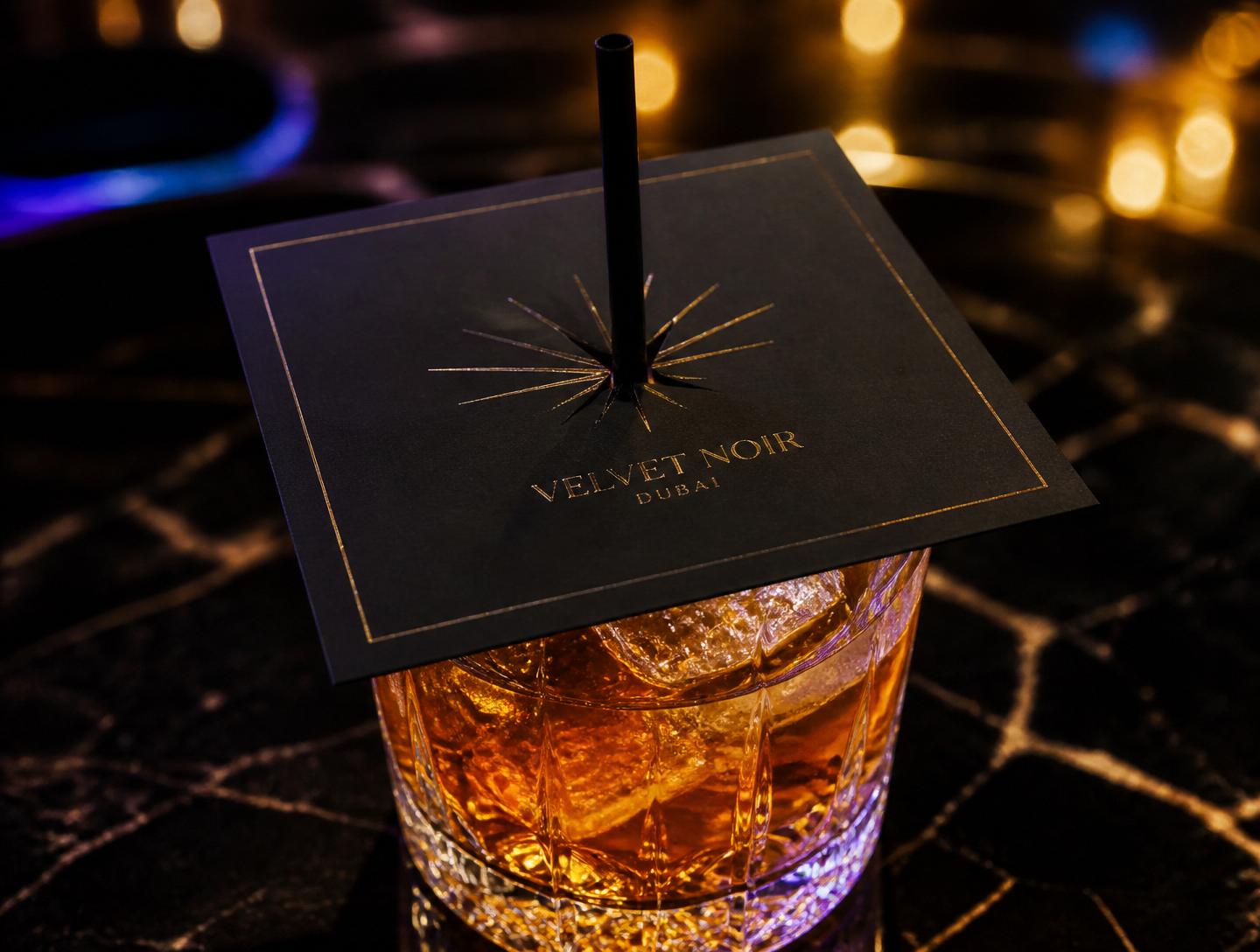 Branded black SafeSip napkin covering a cocktail glass with a straw through the center slit